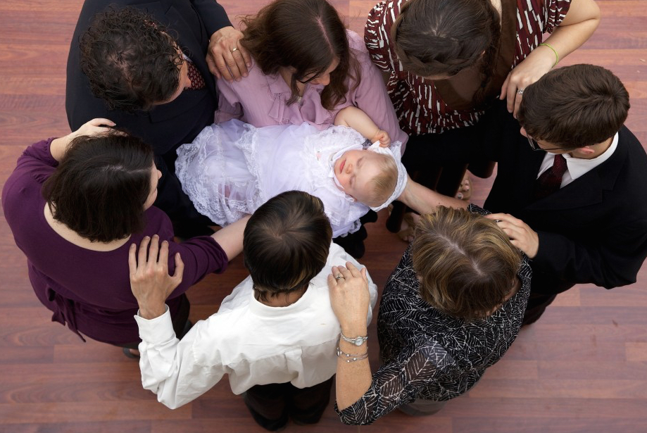 Men and women stand together in a circle, for a baby bless.