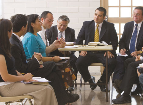 A group of men and women, dressed in Sunday clothes, in a meeting together.
