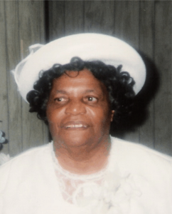 A stately looking, elderly Black woman (standing erect) dressed in all white with a matching hat.