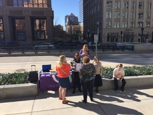 People standing at Ordain Women table on the sidewalk.