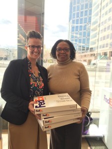 Two women holding four Fed Ex packages.