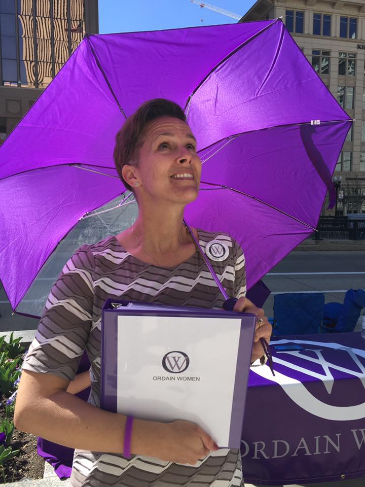 Debra Jenson, standing under an Ordain Women umbrella.