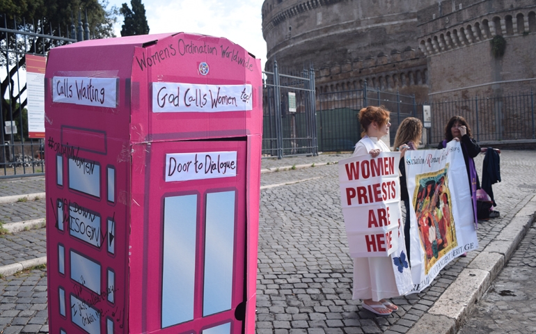 Picture of the Jubilee, a pink confessional booth, and women holding signs