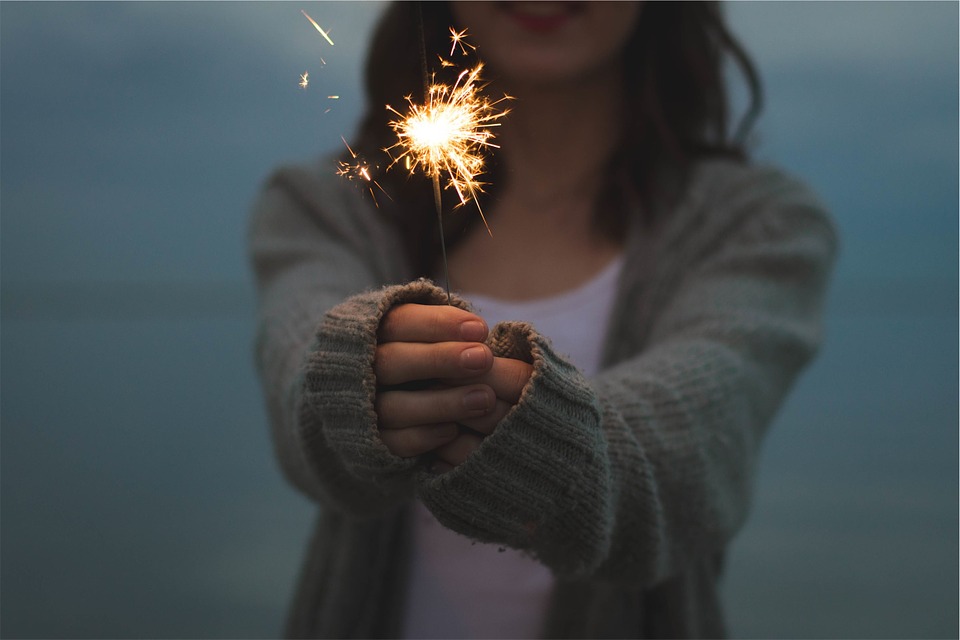 A woman holding out a sparkler.
