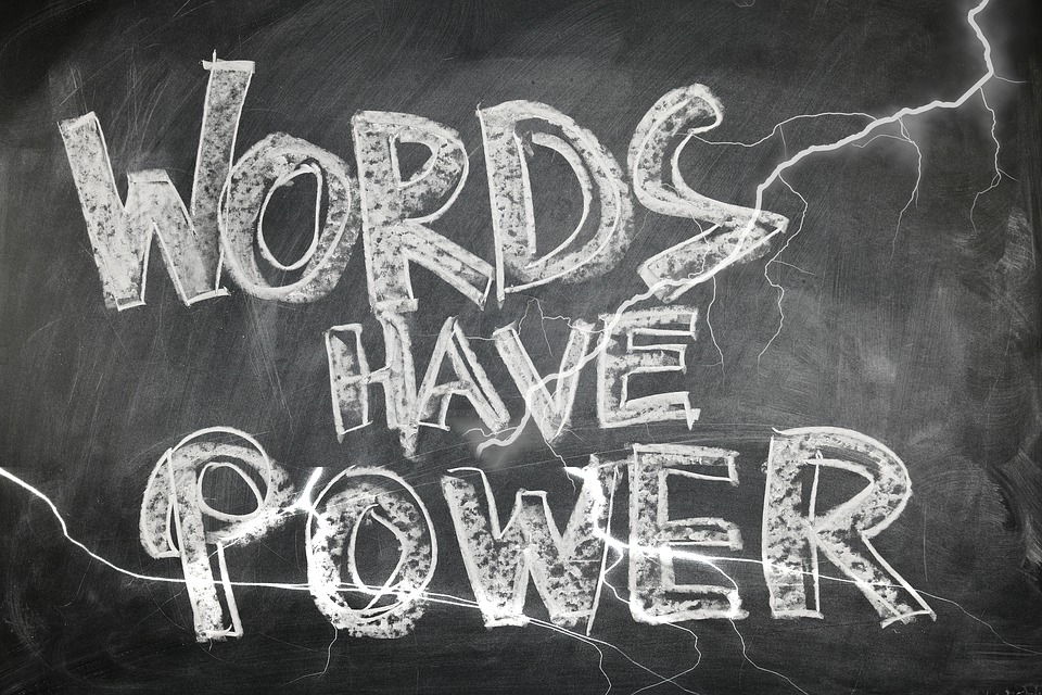 The phrase "words have power" are written in white chalk on a chalkboard, with electricity sparks drawn through the letters.
