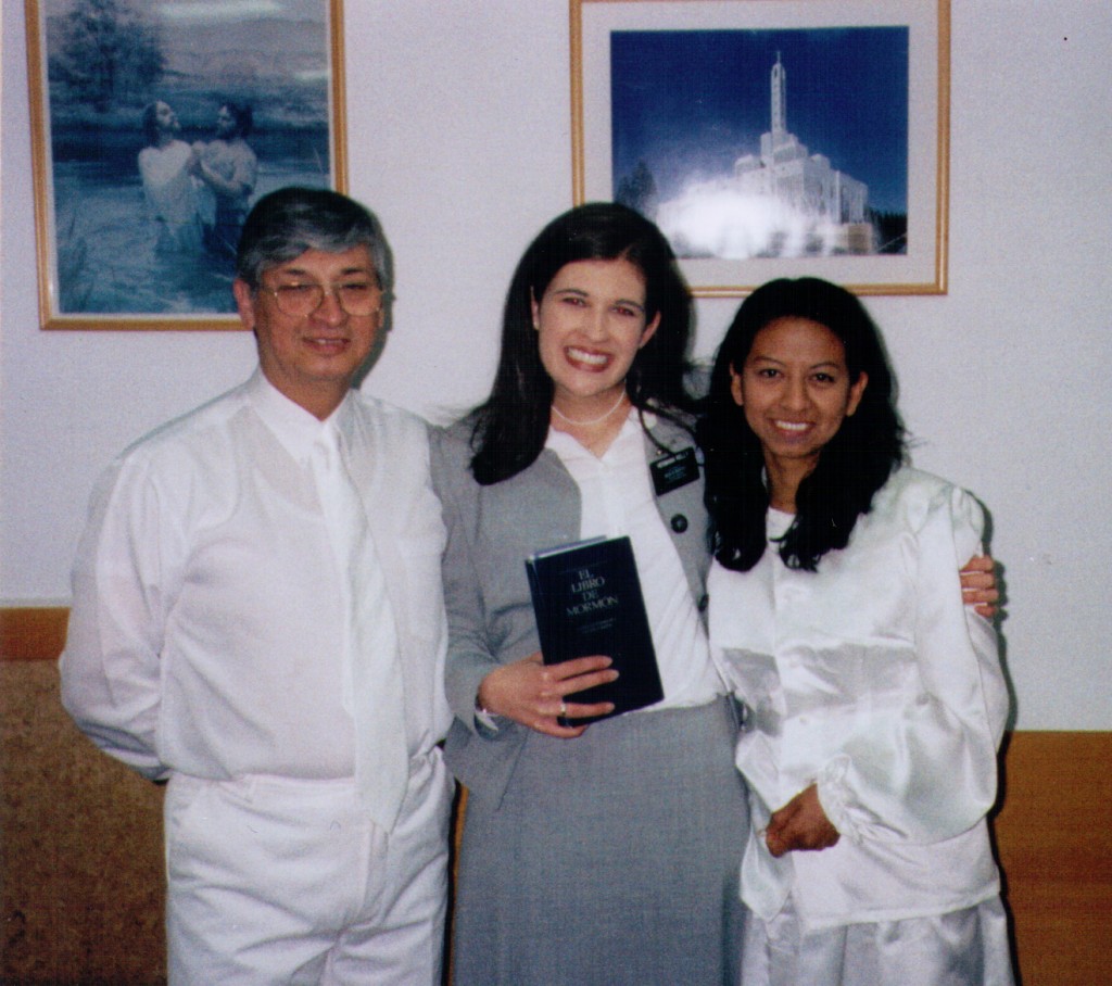 Kate as a sister missionary, smiling with a couple who are wearing baptismal clothes